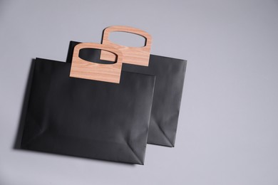 Two black paper shopping bags on grey background, top view. Space for text