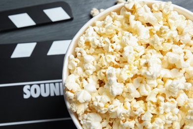 Photo of Fresh tasty popcorn in bucket on table, top view with space for text. Cinema snack