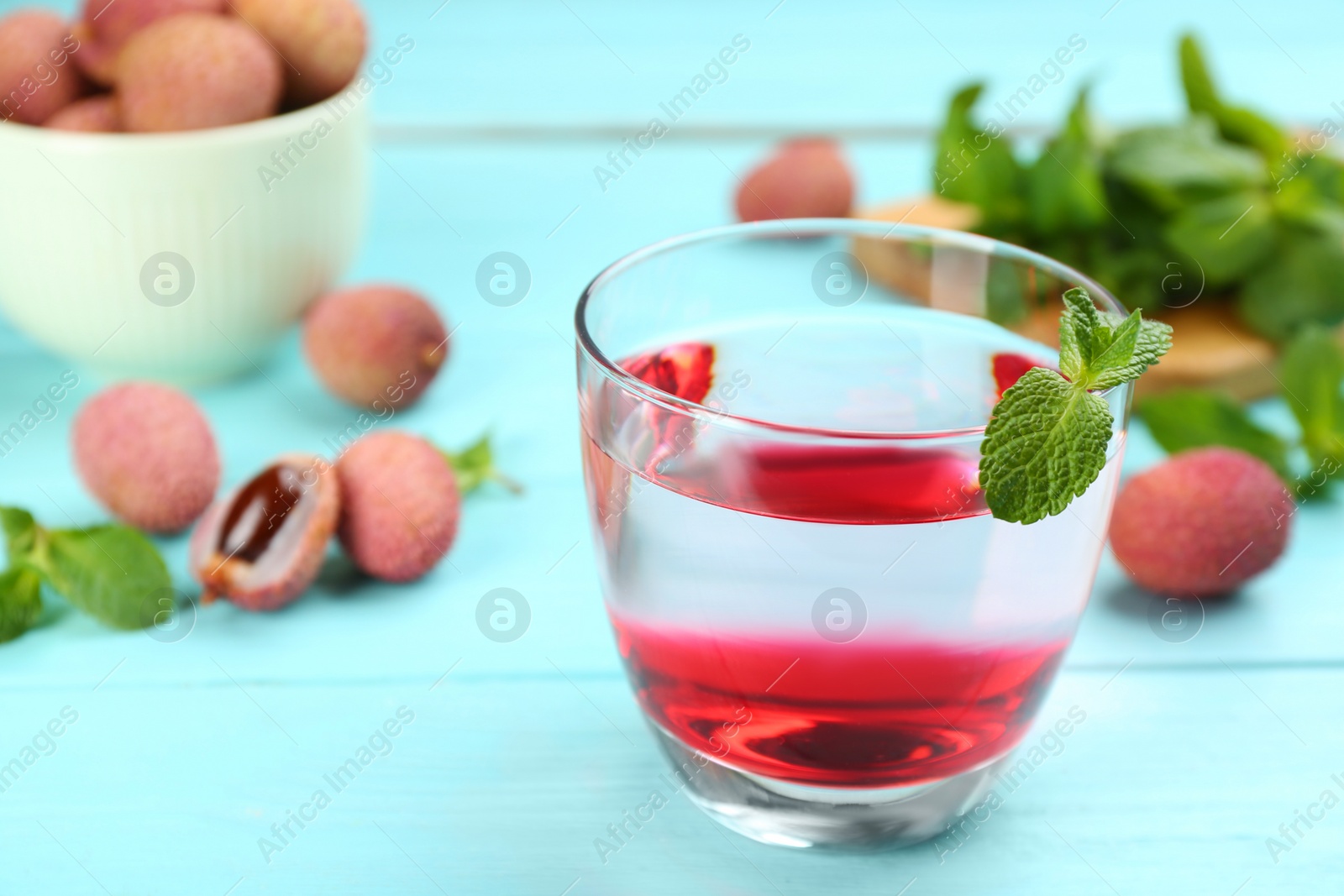 Photo of Lychee cocktail with mint on cyan wooden table, closeup