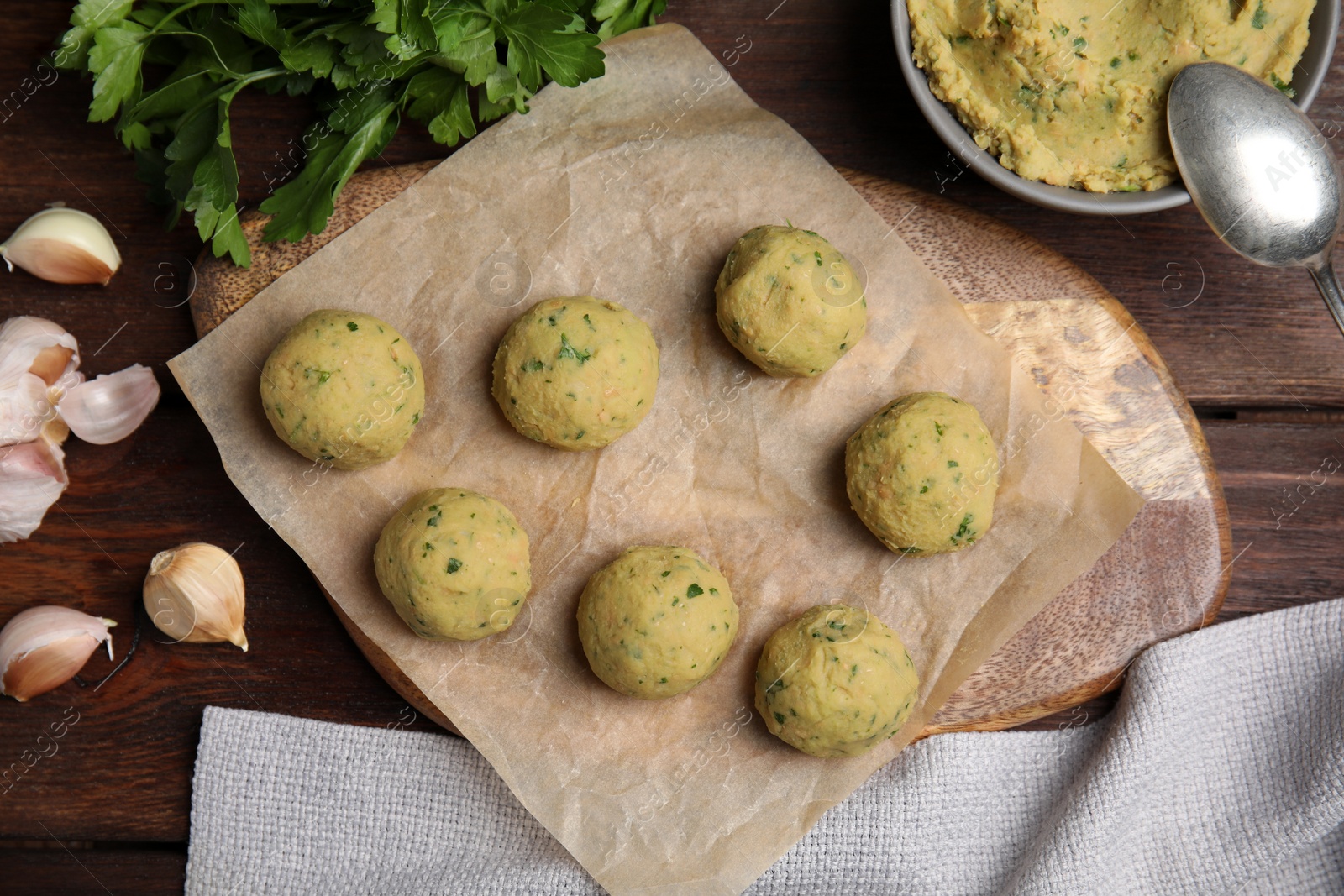 Photo of Raw falafel balls and ingredients on wooden table, flat lay