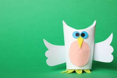 Photo of Toy owl made of toilet paper hub on green background. Space for text