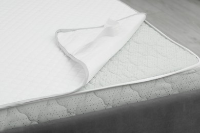 Photo of Soft mattress and protector on bed, closeup