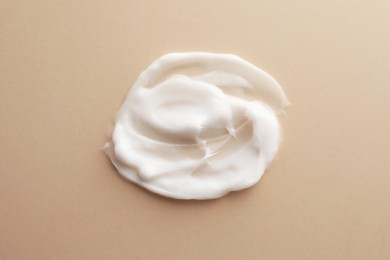 Sample facial cream on beige background, top view