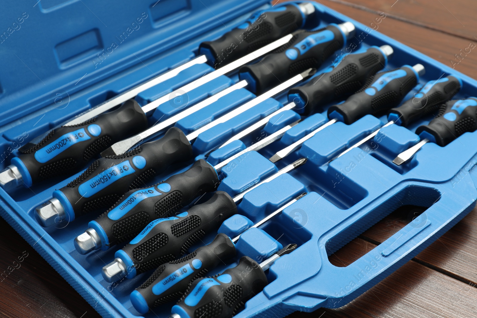 Photo of Set of screwdrivers in open toolbox on wooden table, closeup