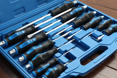 Set of screwdrivers in open toolbox on wooden table, closeup