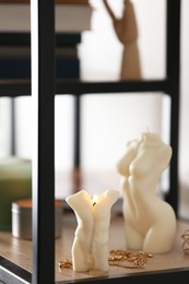 Beautiful body shaped candles and jewelry on shelf indoors