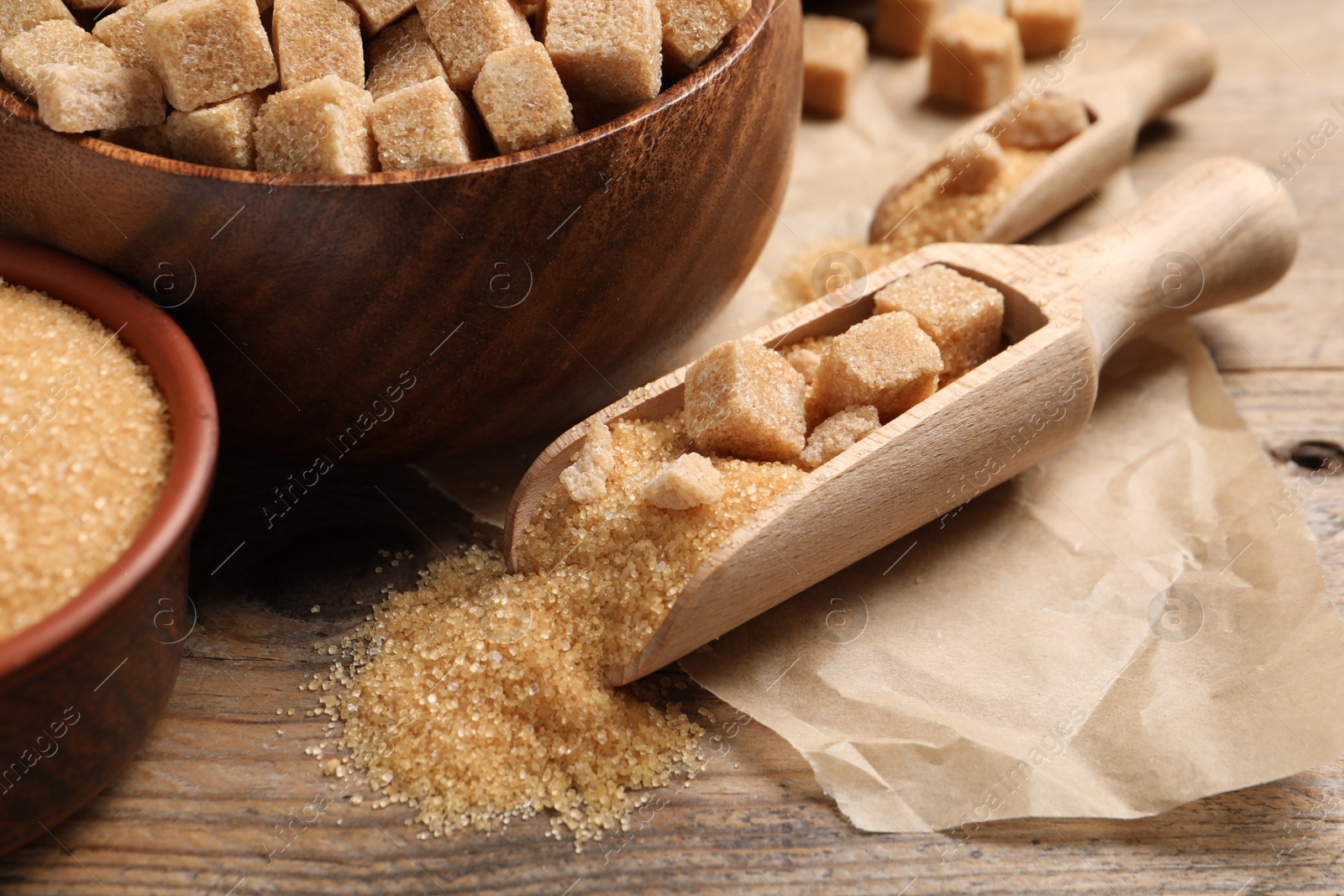 Photo of Scoop with brown sugar on wooden table, closeup