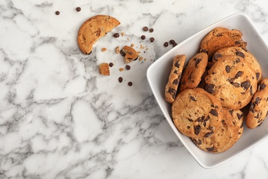 Photo of Bowl with chocolate chip cookies and space for text on marble background, top view