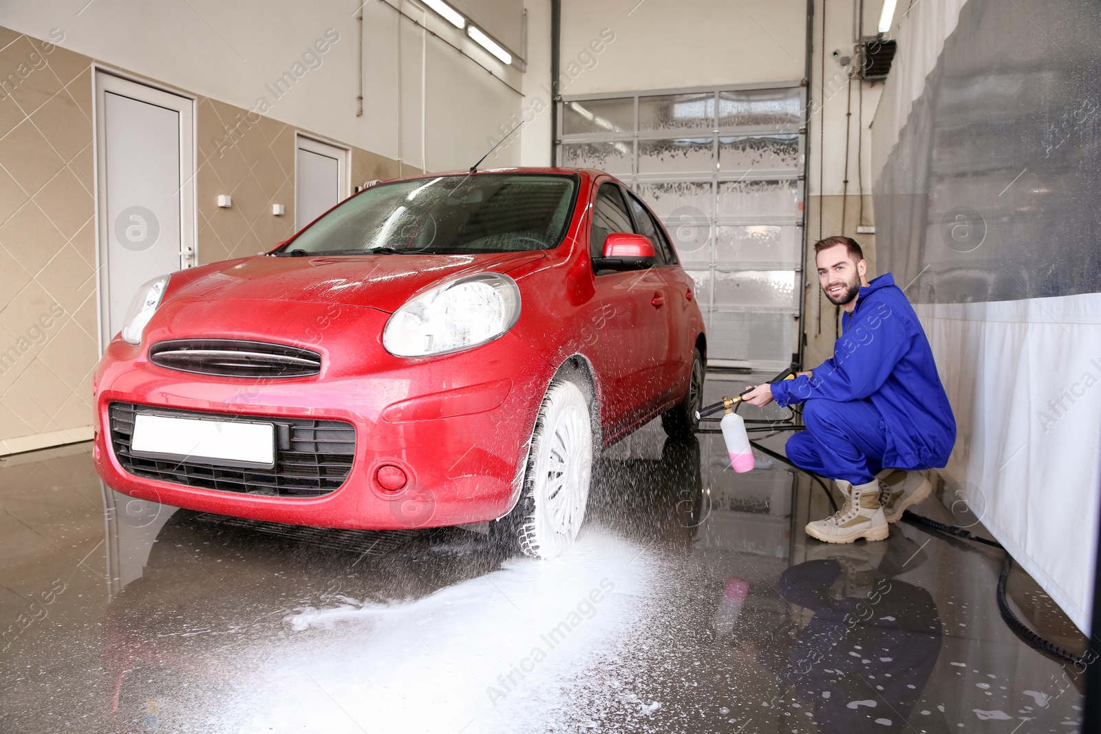 Photo of Worker cleaning automobile with high pressure water jet at car wash