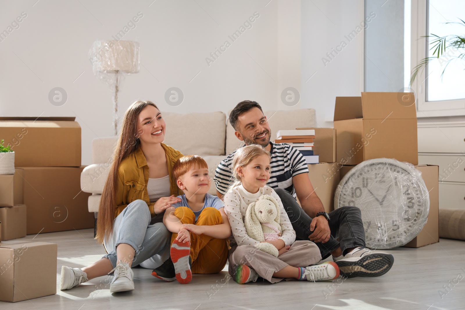 Photo of Happy family sitting on floor in new apartment. Moving day