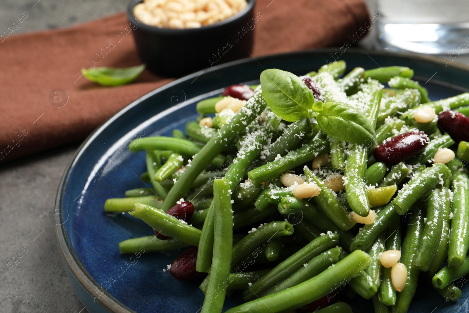 Photo of Plate of tasty salad with green beans on grey table, closeup