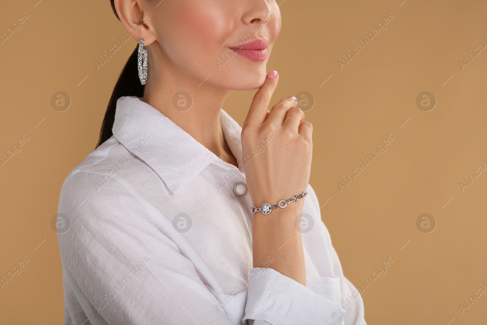 Photo of Young woman with elegant jewelry on beige background, closeup
