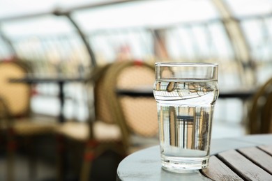 Glass of fresh water on table outdoors. Space for text