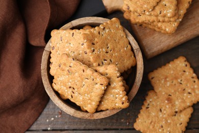 Photo of Cereal crackers with flax and sesame seeds on wooden table, flat lay