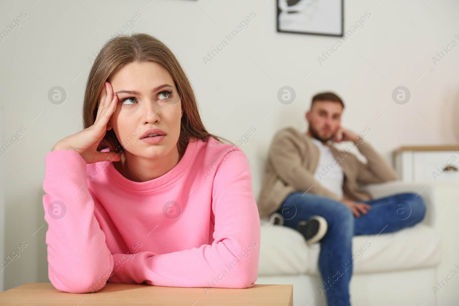 Photo of Young couple ignoring each other after argument in living room. Relationship problems