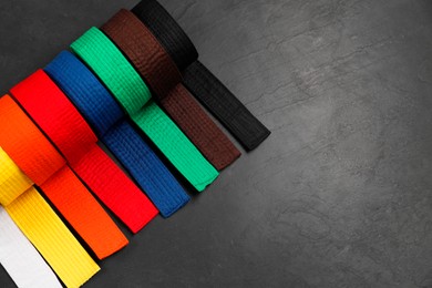 Photo of Colorful karate belts on gray background, flat lay. Space for text