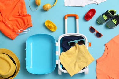 Flat lay composition with child suitcase and accessories on blue background. Summer vacation