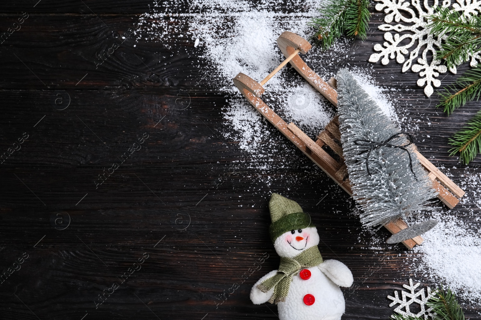 Photo of Flat lay composition with sleigh, decorative Christmas tree and toy snowman on black wooden table. Space for text