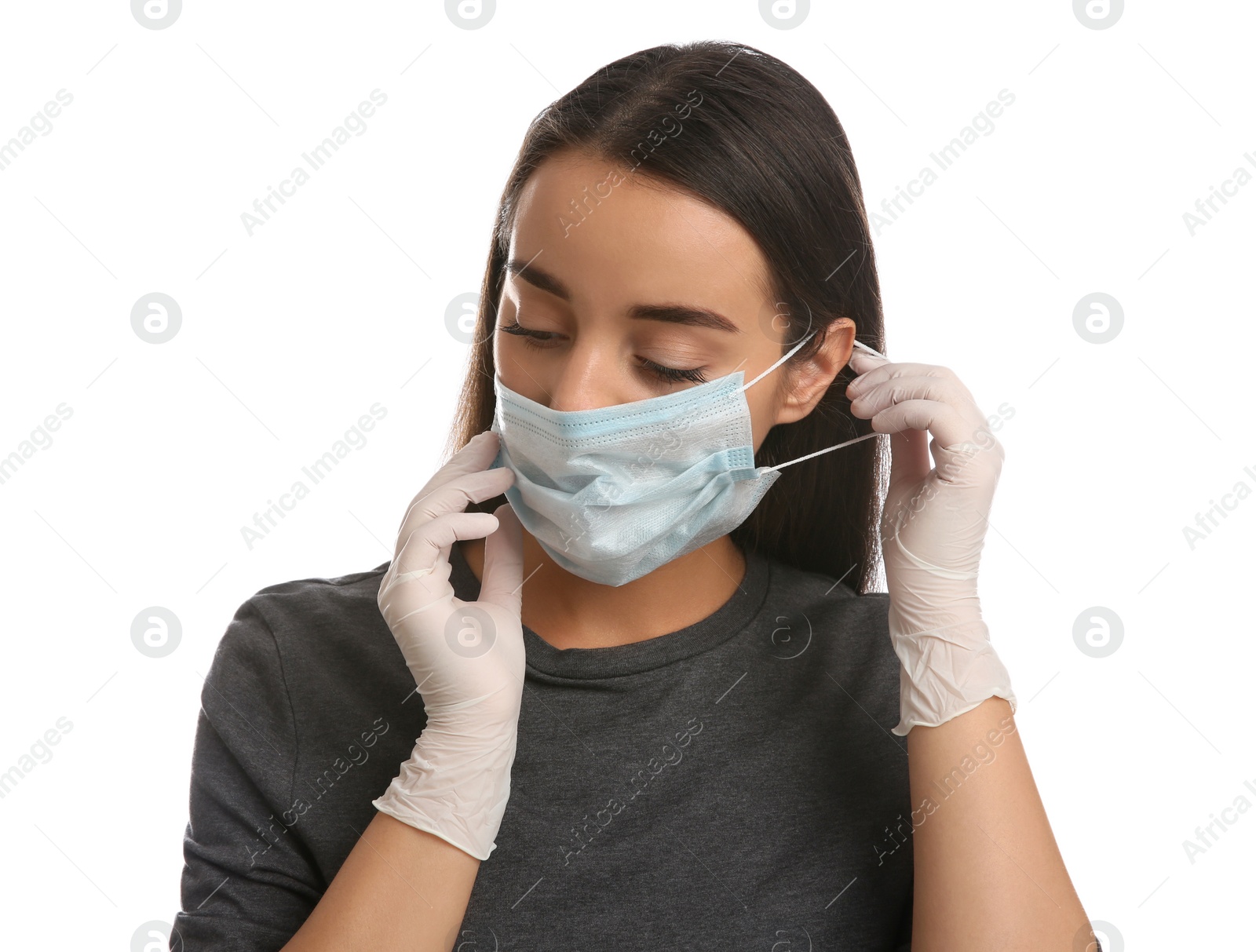 Photo of Woman in medical gloves putting on protective face mask against white background