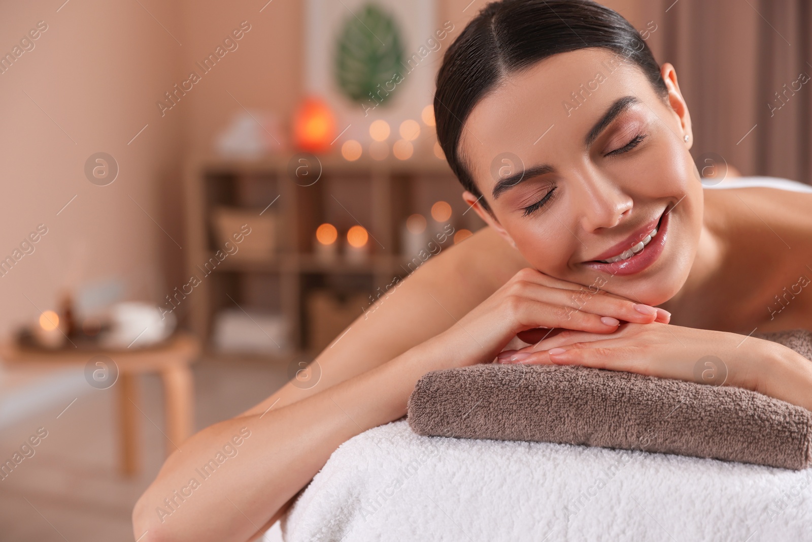 Photo of Young woman resting on massage couch in spa salon, space for text