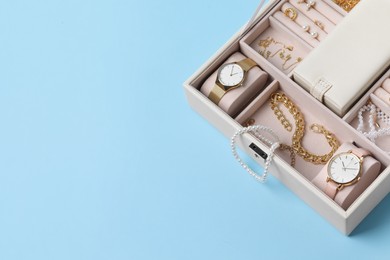 Photo of Jewelry box with many different accessories on light blue background, above view. Space for text