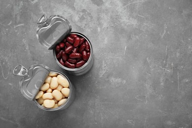 Photo of Tin cans with different canned kidney beans on grey table, flat lay. Space for text