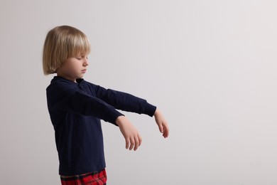 Boy in pajamas sleepwalking on white background, space for text