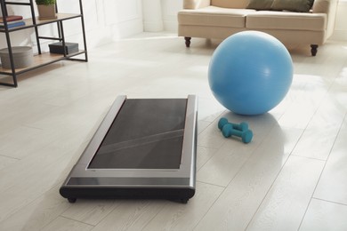 Modern walking treadmill, dumbbells and fitness ball in living room. Home gym equipment