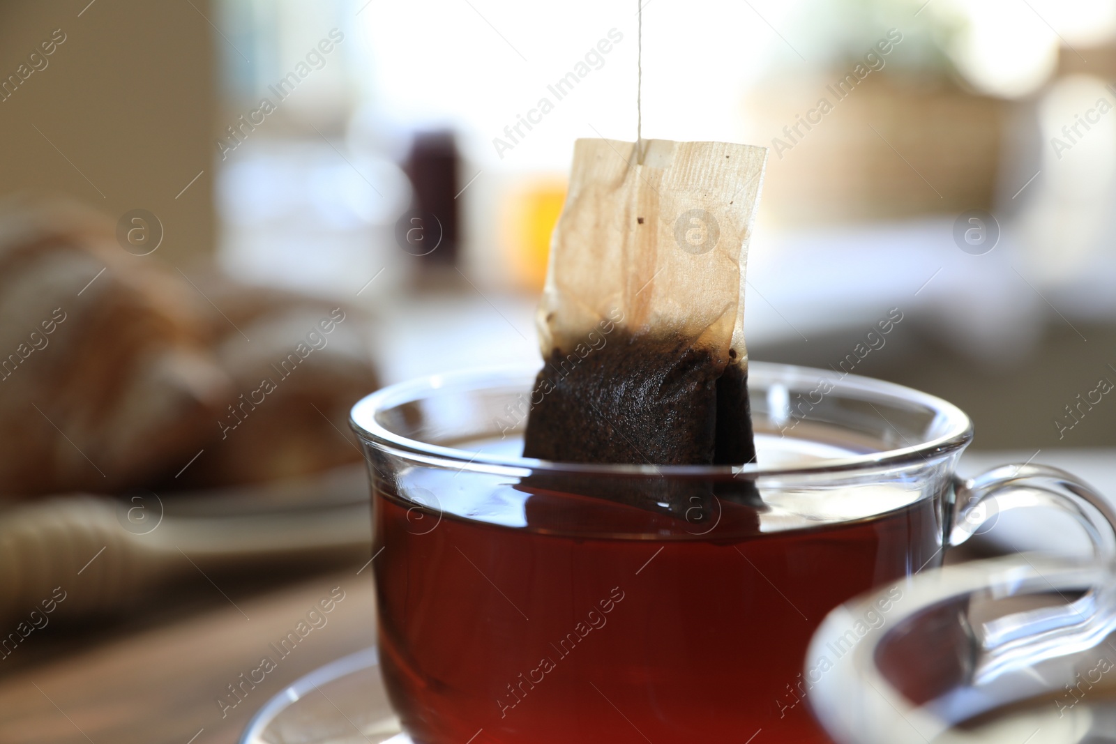 Photo of Tea bag in glass cup on table indoors, closeup