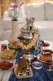 Photo of Traditional Russian samovar with treats on white table at home