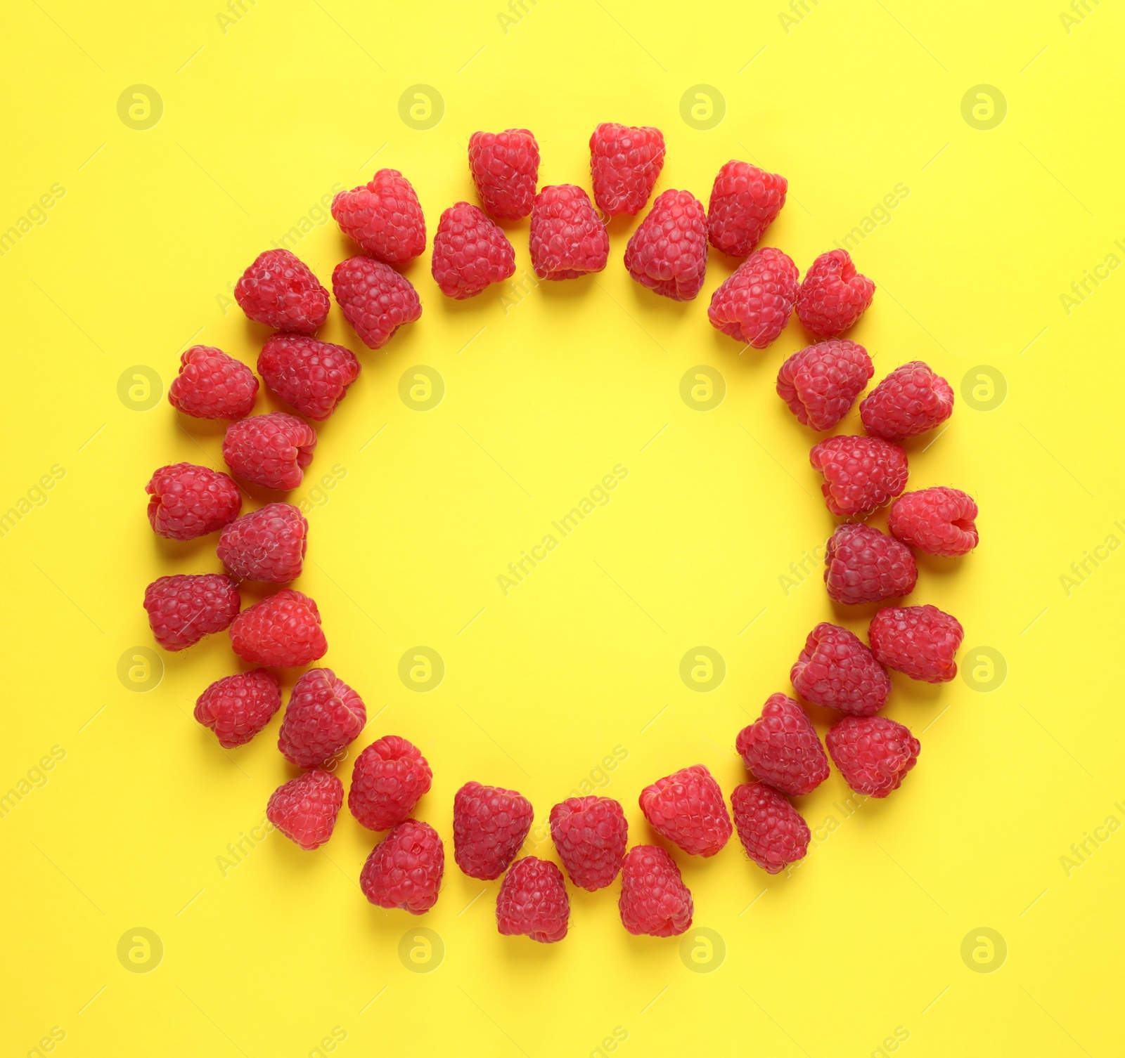 Photo of Frame of delicious ripe raspberries on yellow background, flat lay. Space for text