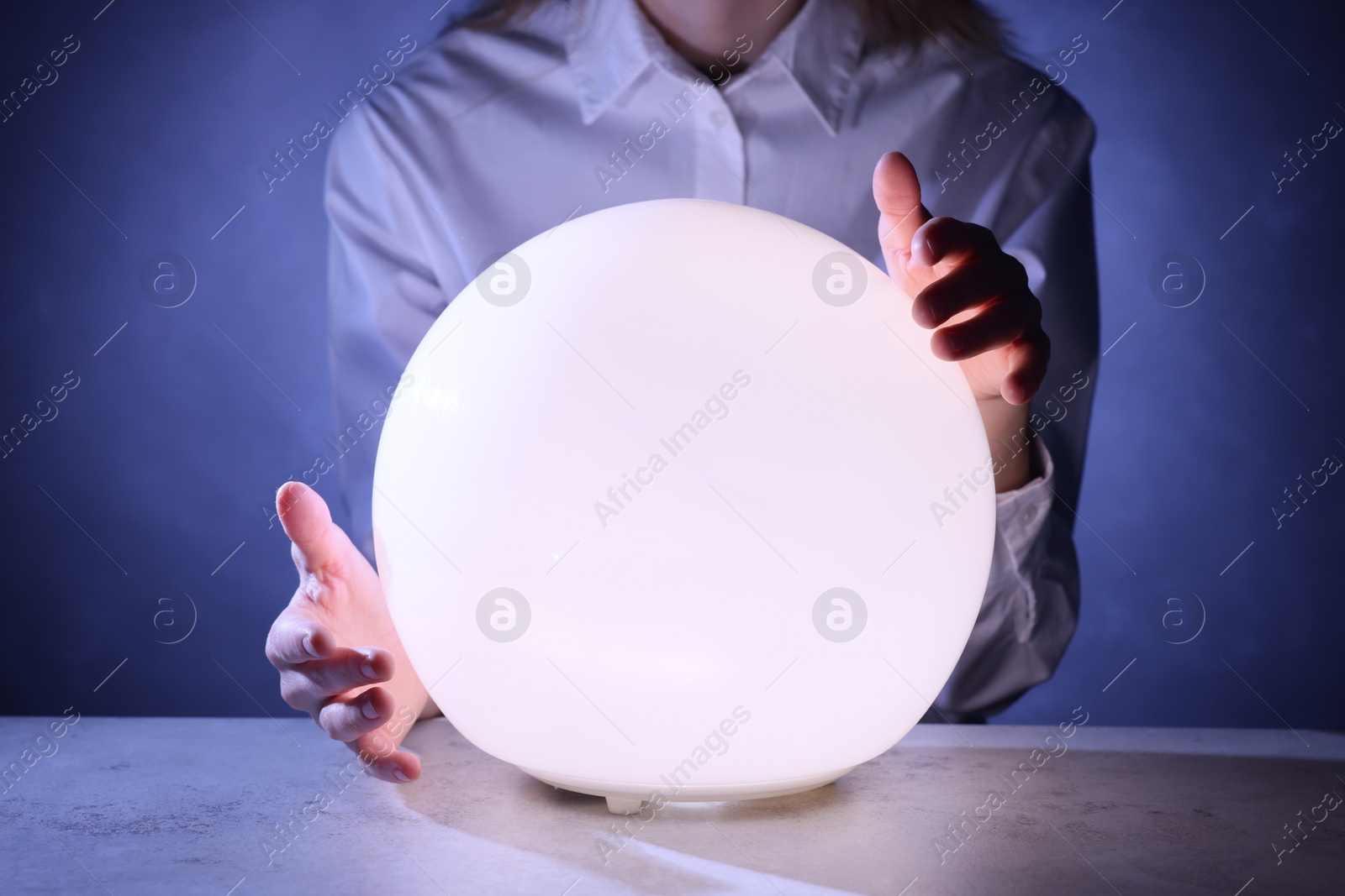 Photo of Businesswoman using glowing crystal ball to predict future at table, closeup. Fortune telling