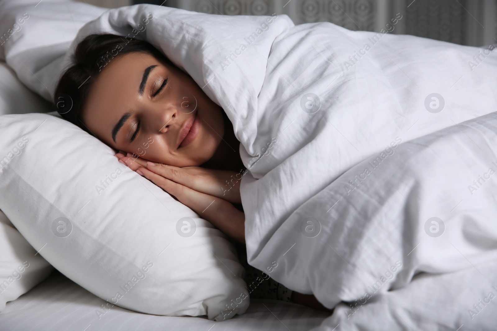 Photo of Young woman sleeping in bed covered with white blanket