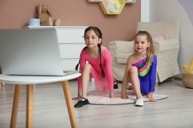 Photo of Cute little girls warming up before online dance class indoors