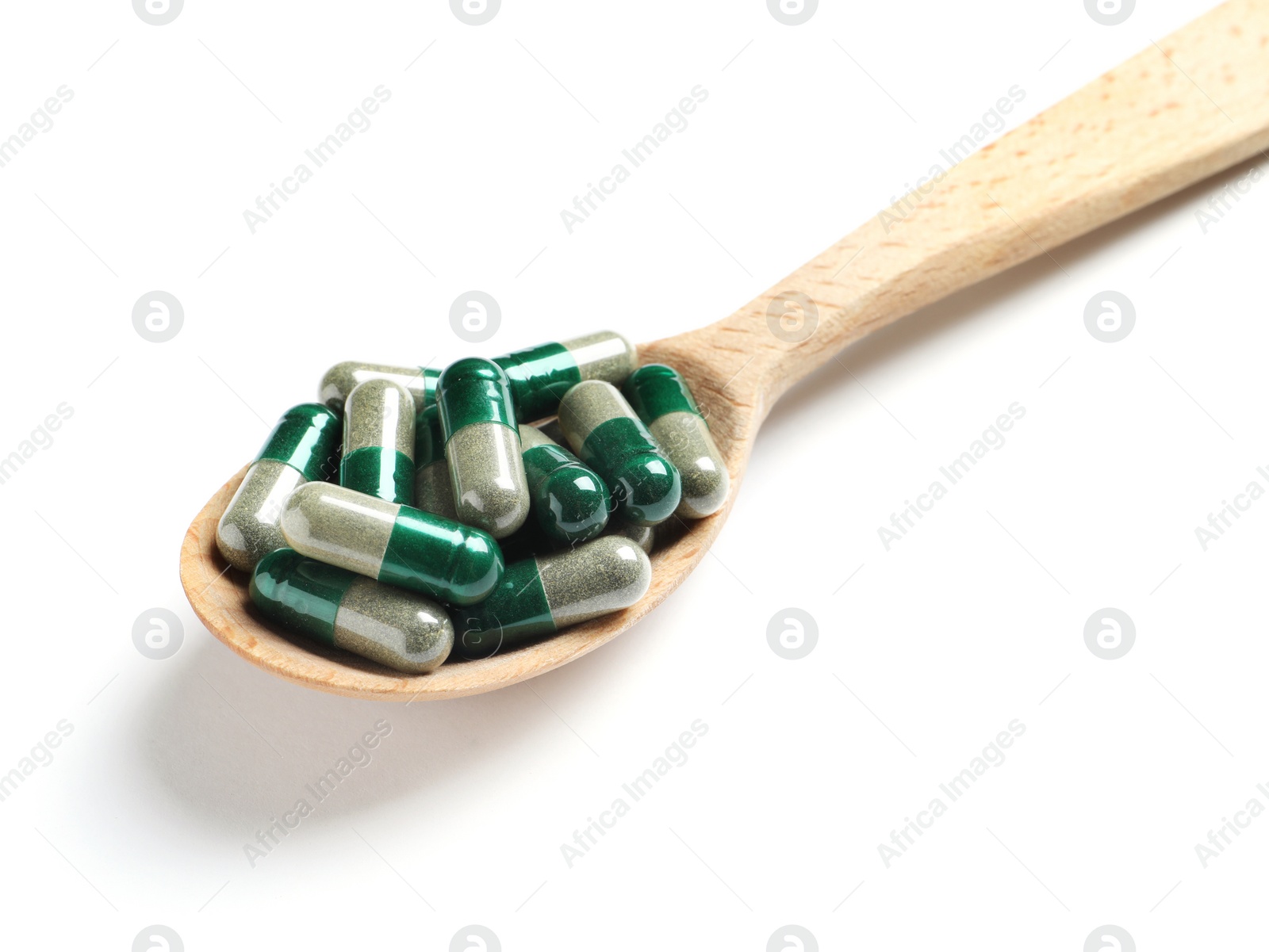 Photo of Wooden spoon with green spirulina capsules on white background