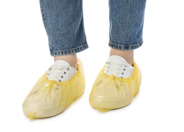 Woman wearing yellow shoe covers onto her sneakers against white background, closeup