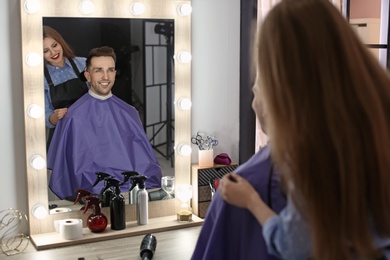 Photo of Professional hairdresser working with client in beauty salon