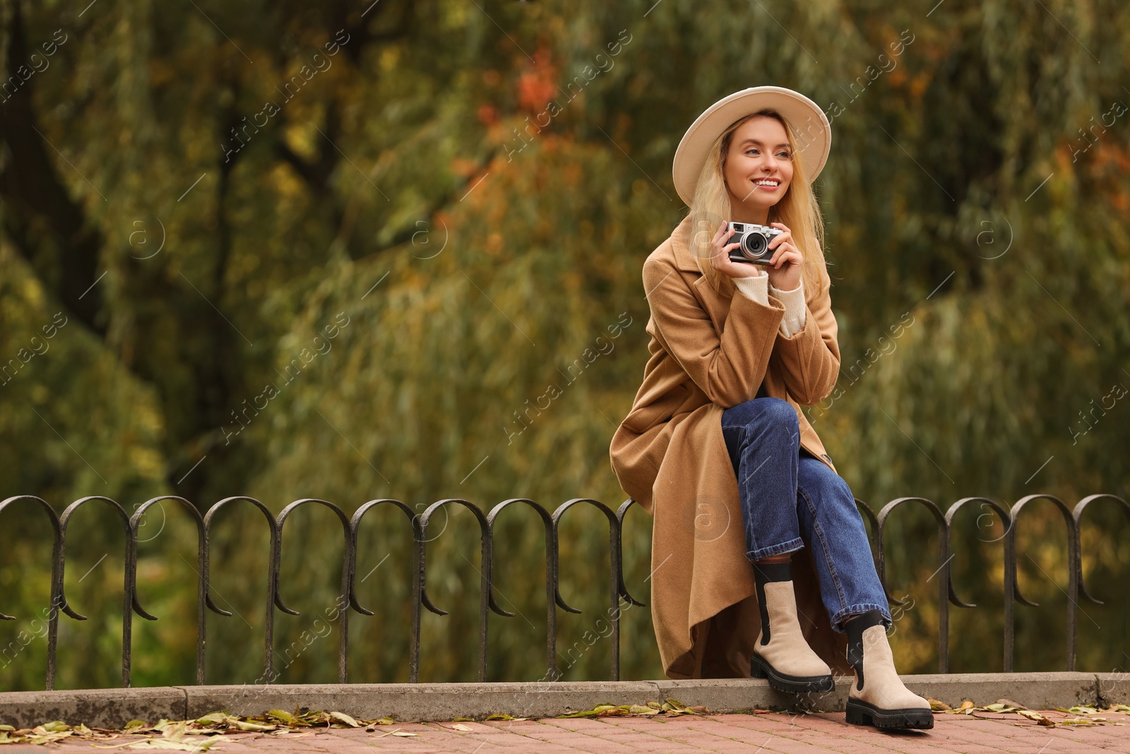 Photo of Happy woman with camera in autumn park. Space for text