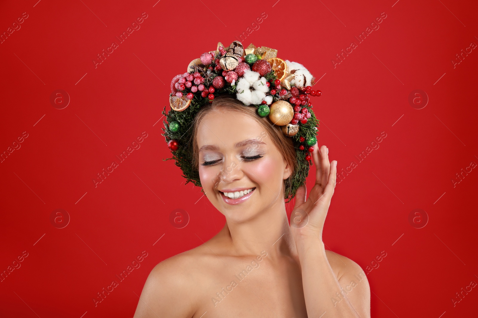 Photo of Beautiful young woman wearing Christmas wreath on red background