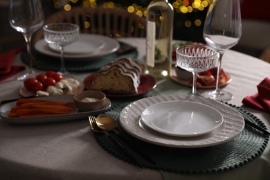 Photo of Christmas table setting with bottle of wine, appetizers and dishware