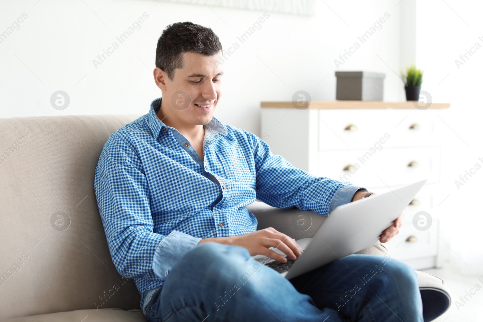 Photo of Portrait of man with laptop on sofa, indoors