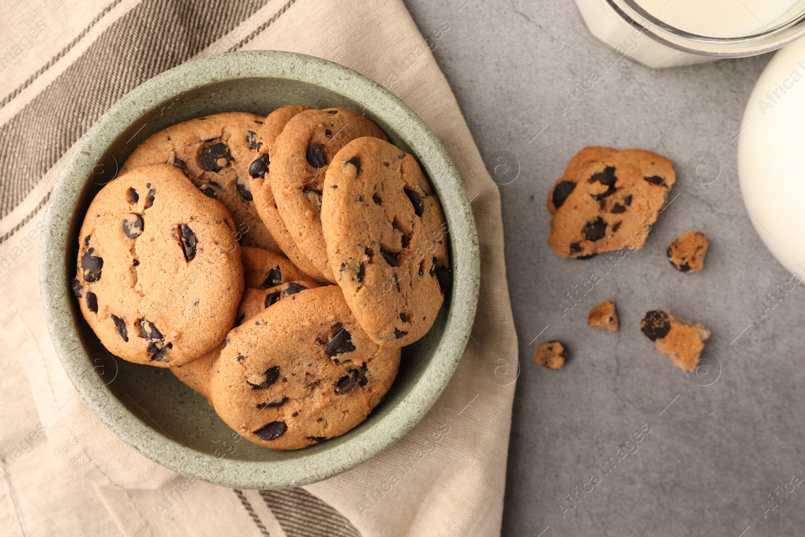 Photo of Delicious chocolate chip cookies and milk on grey table, flat lay