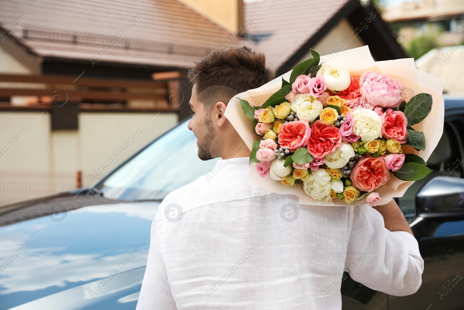 Photo of Young man with beautiful flower bouquet near car outdoors