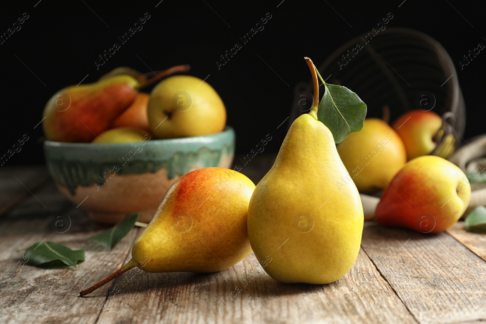 Photo of Ripe pears on wooden table against dark background