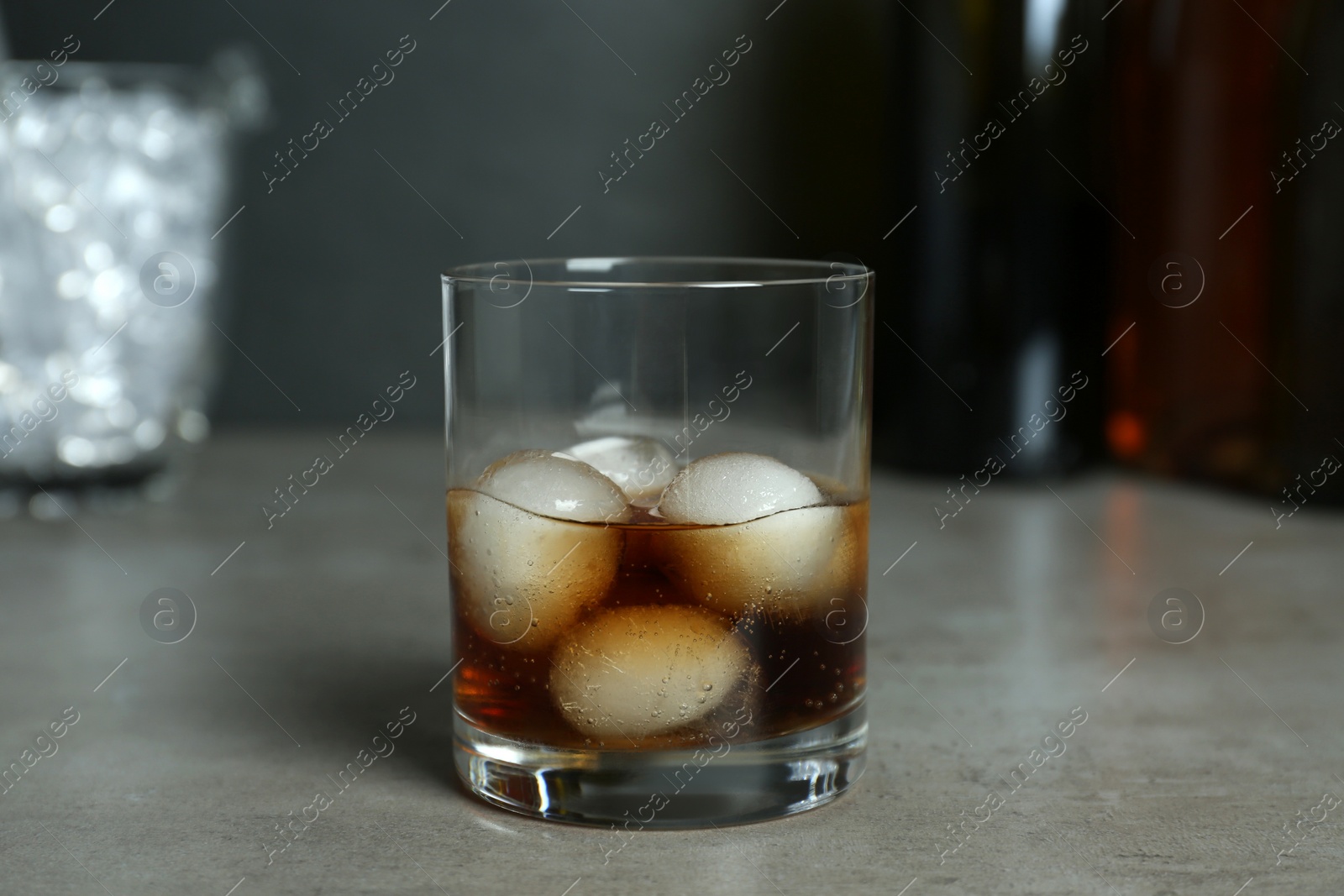 Photo of Delicious cocktail with ice balls on grey table