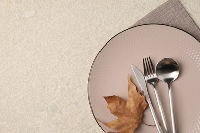 Stylish table setting with cutlery and dry leaf on light surface, top view. Space for text