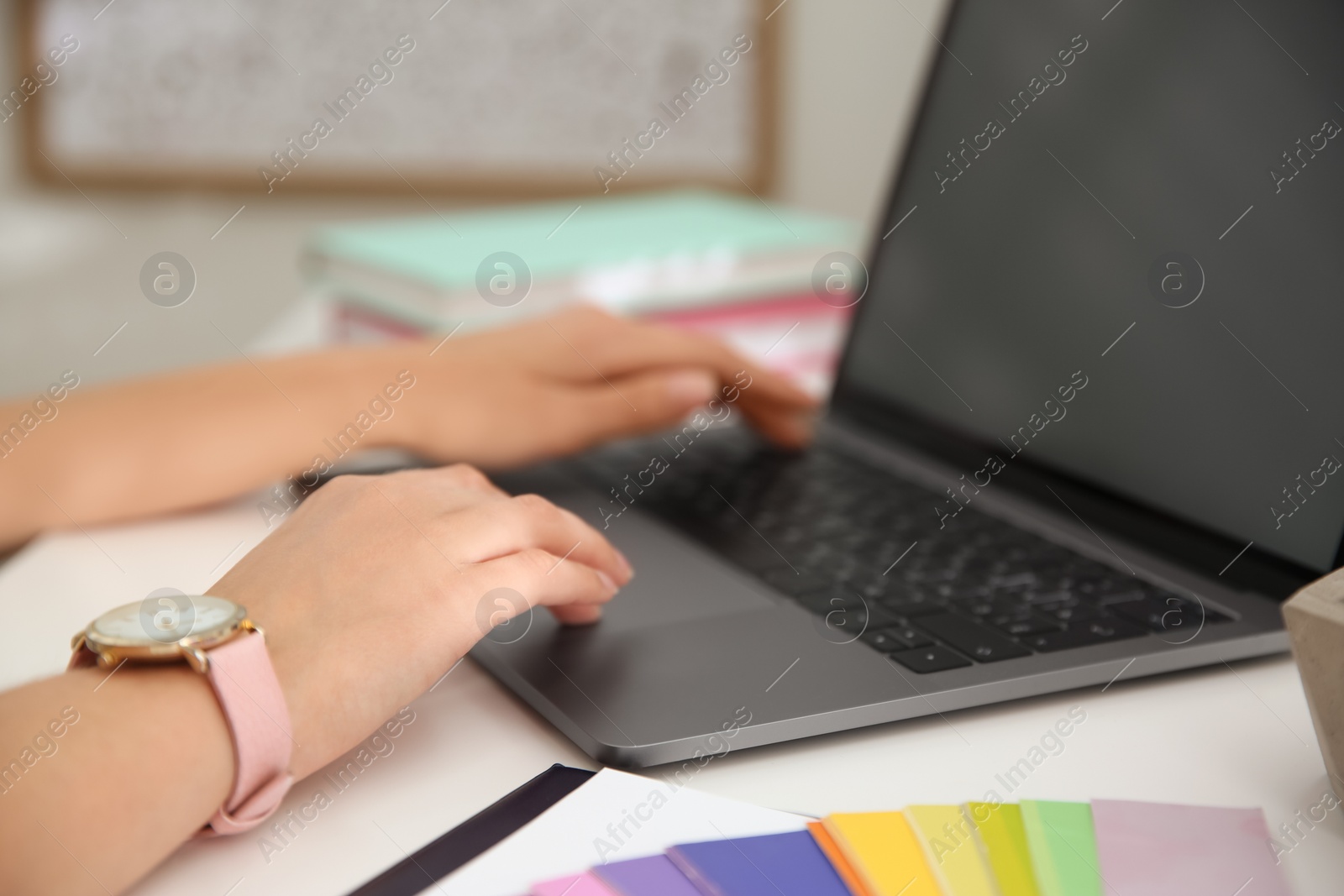 Photo of Woman working with modern laptop at white table, closeup