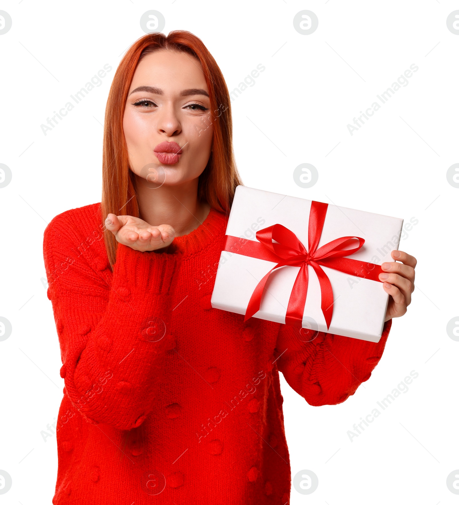 Photo of Young woman in red sweater with Christmas gift blowing kiss on white background