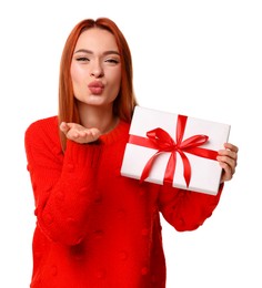 Photo of Young woman in red sweater with Christmas gift blowing kiss on white background