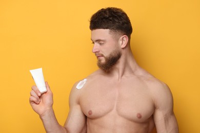 Photo of Handsome man with moisturizing cream on orange background